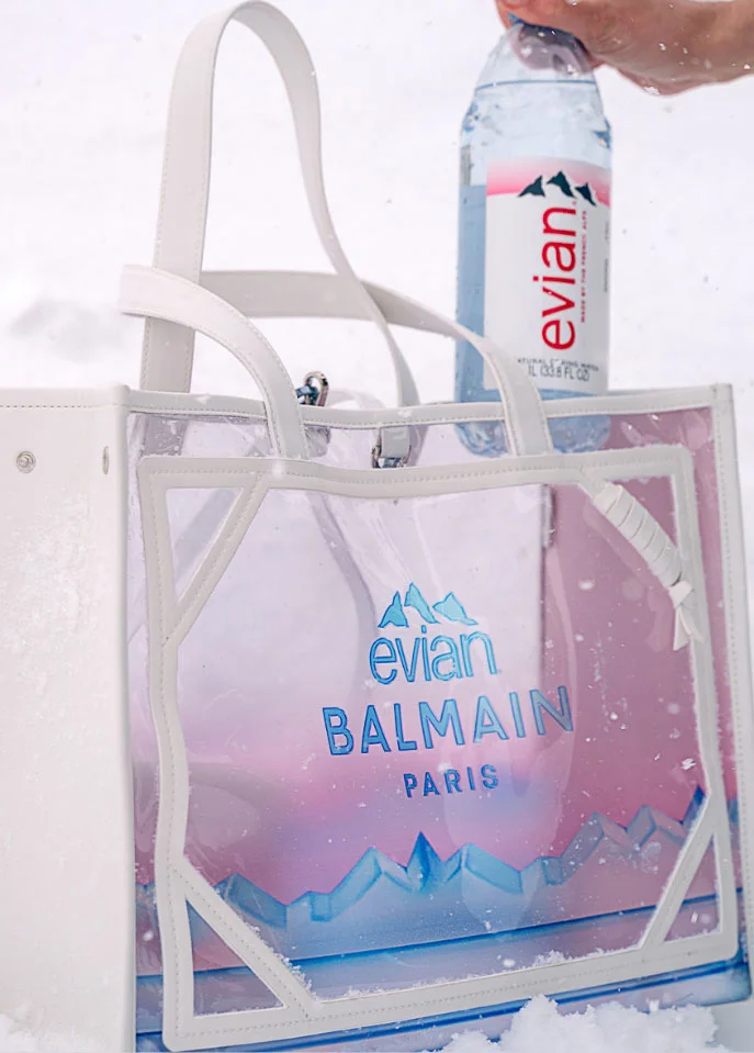 evian water bottle being placed in a tote bag from the evian and balmain collection 